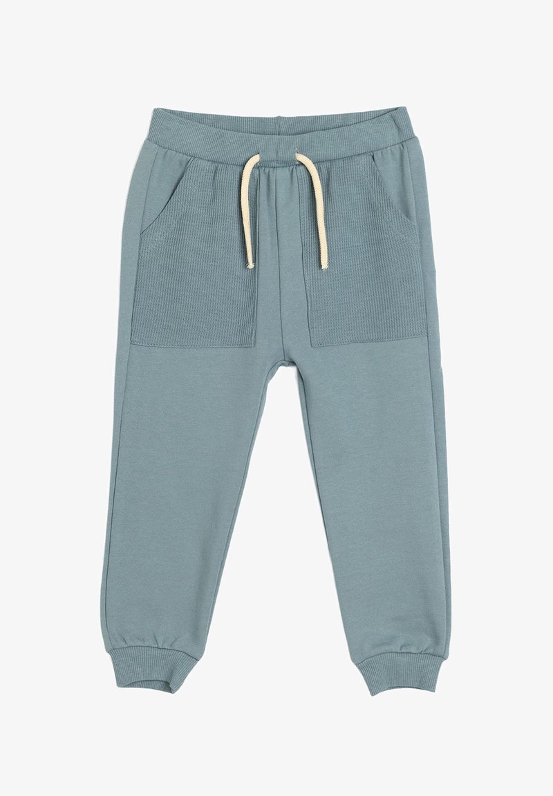 Pantalones de chándal azul claro con bolsillos frontales acanalados, cintura elástica, cordón crema y puños ajustados. Fabricados en suave material de algodón.