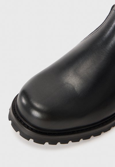 Musthave must saapad mustast nahast, ümarate varvastega, sileda tekstuuriga ja paksu kummitaldiga, millel on profiilse muster.