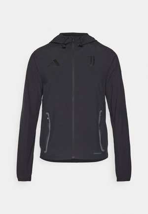 Veste de sport noire avec capuche, dotée de poches zippées, logo Adidas et emblème de la Juventus. Fabriquée en tissu léger et texturé.