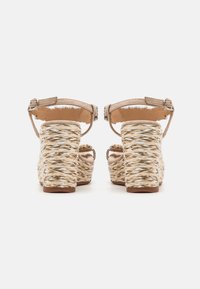 Sandales compensées avec une tige en faux suède beige, une bride de cheville et un talon en jute tissé aux tons naturels avec une finition texturée et tressée.