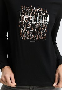 Black long-sleeve shirt with abstract brown and white pattern and the word "beautiful" in large white letters, with "Tom Tailor" below the design.