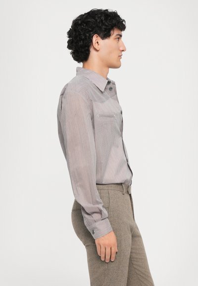 Helepa pika, kerge hall pusa, millel on peened horisontaalsed triibud, tasku, nööbid varrukatel ja struktureeritud krae.