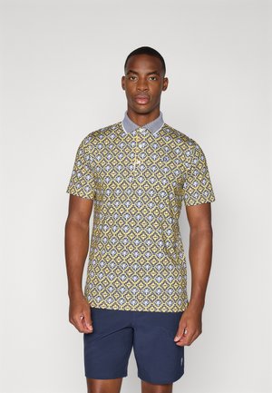 Lühikeste varrukatega polo särk, millel on kollane geomeetriline muster, sinised aktsendid ja helesinine krae. Kandsid navy-blue šortse.