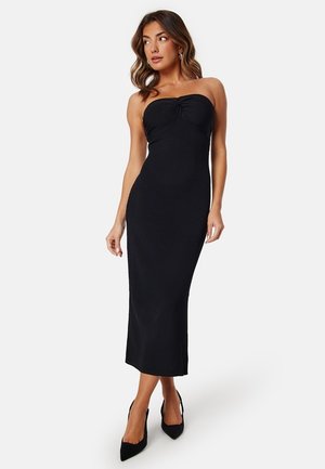 Abito midi senza spalline nero a costine con dettaglio a torsione sul décolleté, silhouette slim e spacco laterale per facilitare i movimenti.