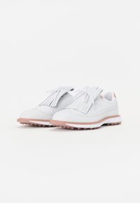 Λευκά δερμάτινα παπούτσια με φούντες, τρυπητό σχέδιο και ροζ καουτσούκ σόλα. Ορατά επίπεδα κορδόνια και ελαφριά επένδυση.