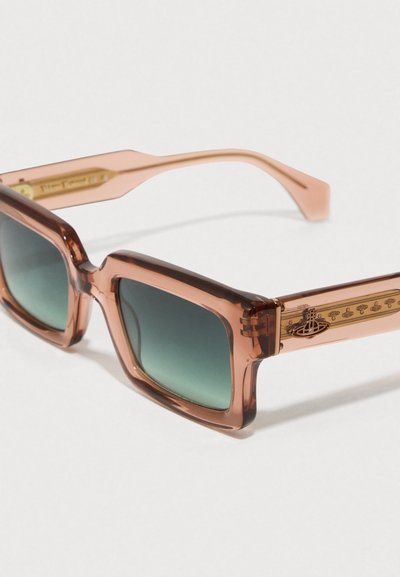 Τετράγωνα γυαλιά ηλίου με διαφανή ροδάκινο χρώμα και φακούς με πράσινη κλίση. Διακοσμημένα με χρυσές λεπτομέρειες στους βραχίονες και υφή στις πλευρές.