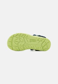Shoe outsole with a textured green rubber surface, featuring a patterned tread for traction and a minimalist design.