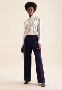White button-up shirt with vertical navy stripes, paired with navy wide-legged trousers. Smooth fabric, tailored fit, and no visible accents.