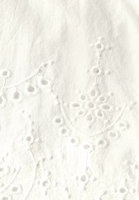 Tessuto bianco ricamato con motivi floreali, lavorazione intricata e accenti in rilievo. Texture liscia con un aspetto delicato e morbido.