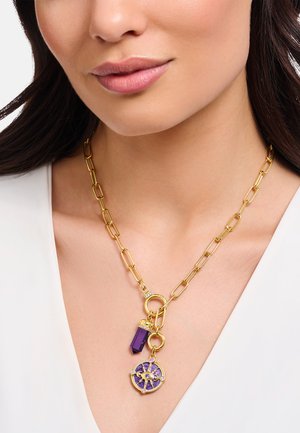 Die goldene Kettenhalskette verfügt über längliche Glieder, einen lila Kristallanhänger und einen dekorativen runden Anhänger mit lila und goldenen Akzenten.
