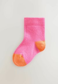 Pink sock with a ribbed texture and orange heel and toe accents. Mid-calf length, smooth knit material.