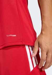 Κόκκινη αθλητική φανέλα από ύφασμα που απομακρύνει την υγρασία με ομαλή υφή. Φέρει λευκό λογότυπο CLIMACOOL και λευκές ρίγες στα σορτς.