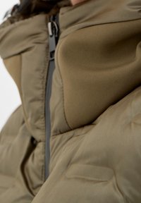 Wyściełana, oliwkowo-zielona kurtka z wysokim kołnierzem, zamkiem błyskawicznym i gładką fakturą, z bocznymi kieszeniami i kontrastowymi szarymi detalami.