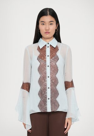 Lyseblå stribet bluse med brune blonde detaljer, krave, knaplukning foran og udvidede ærmer. Blød, gennemsigtig stof.