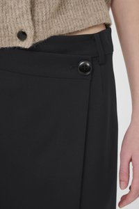 Black trousers featuring a smooth texture, with a side pleat and a decorative black button detail at the waist.