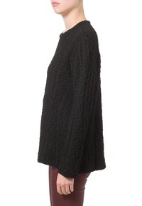 Mujer con una camiseta negra acolchada de manga larga y pantalones granates, mostrada de lado sobre un fondo blanco.