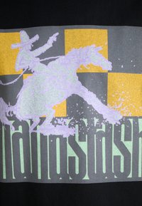 Schwarzes Grafik-T-Shirt mit einem helllila Cowboy auf einem Pferd, vor einem gelben und grauen Quadrat-Hintergrund und fettem grünen Text darunter.