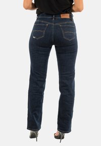 Jeans de denim azul oscuro con pierna recta, que presentan dos bolsillos traseros con costuras en contraste y un parche de cuero de marca en la cintura.