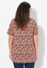 Top de manga corta con estampado floral en un fondo gris oscuro y patrones de flores coral. Textura suave y ajuste relajado.