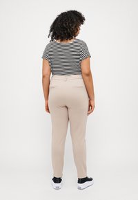 Striped black and white t-shirt, beige trousers with an elastic waistband and side pockets, paired with black sneakers. Textured hair visible.