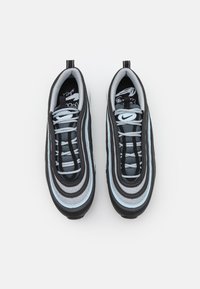 Svarta och gråa träningsskor med ett lager av vågmönster, som har ljusblå accenter, mesh- och lädermaterial samt en texturerad sula.