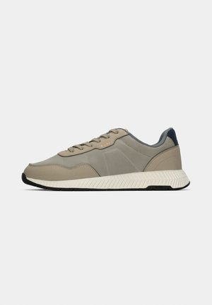 Baskets basses beige et grises avec semelle texturée blanche et fermeture à lacets, montrant la vue extérieure sur un fond uni.