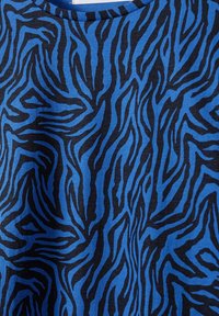 Blå tyg med svart zebramönster och synlig söm vid rund halsringning.