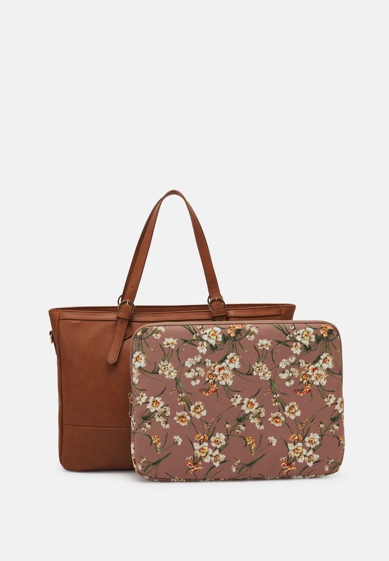 Sac cabas en cuir marron avec une housse pour ordinateur portable amovible à motif floral présentant des fleurs blanches et orange sur fond mauve.