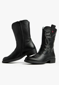 Bottes de cowboy en cuir noir avec une fermeture éclair latérale, motifs d'étoiles brodés en argent et rouge, et un petit talon carré.