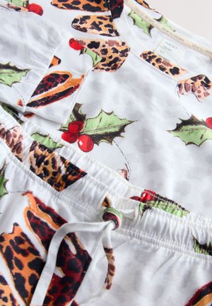 Ensemble de pyjama en tissu blanc avec un imprimé festif comprenant des taches de léopard, des feuilles de houx et des baies rouges, doté d'une taille à cordon et de manches courtes.