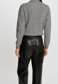 Harmaa neulottu villapaita, jossa on korkea kaulus ja ribbidesain, yhdistettynä mustiin nahkahousuihin, joissa on takataskut ja sileä pinta.