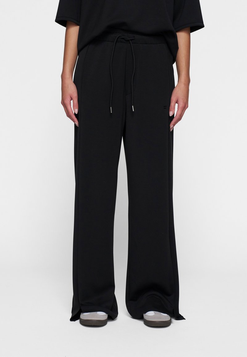 Zwarte wijdvallende sweatpants van zachte stof, met een elastische tailleband met een trekkoord en zijzakken.