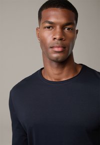Navy blue long-sleeve shirt made of soft fabric with a round neckline and a smooth texture. Features minimalistic design, no patterns or embellishments.
