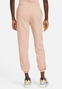 Ljusrosa sweatpants med elastiska muddar och sidofickor, tillverkade av mjukt tyg. Kombineras med flersidiga sneakers med en kraftig sula.