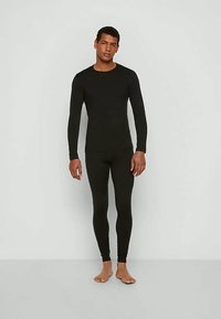 Melnas garām piedurknēm topiņš un saderīgas legingi, izgatavoti no gludas, elastīgas auduma, paredzēti pieguļoša silueta un komforta nodrošināšanai.