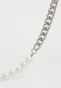 Chain necklace featuring silver links and white round pearls, with a smooth finish and a secure clasp for closure.
