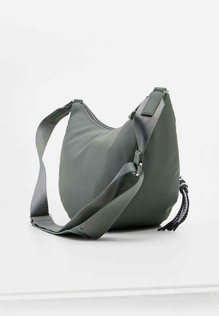 Bolso de hombro de nailon gris con forma redondeada, correa ajustable y cierre de cremallera. Presenta un acento texturizado y un tassel decorativo.