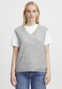 Grauer gestrickter Weste mit V-Ausschnitt und Rautenmuster, über einem weißen T-Shirt getragen. Das Material wirkt weich mit einer leicht strukturierten Oberfläche.