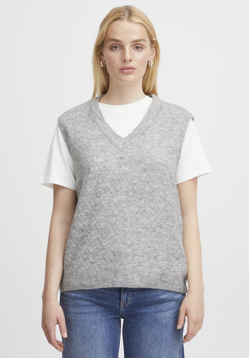Grauer gestrickter Weste mit V-Ausschnitt und Rautenmuster, über einem weißen T-Shirt getragen. Das Material wirkt weich mit einer leicht strukturierten Oberfläche.
