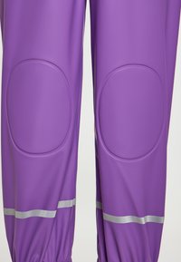 Violet neperskandžios kelnės su apvaliais kelių įklotais, elastingais nusmukimo kraštais ir sidabrinėmis atspindinčiomis juostomis. Sklandži medžiaga, patvari ir pagerinanti funkcionalumą.