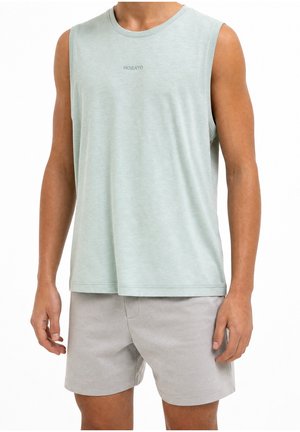 Torso masculino con camiseta sin mangas de color verde claro con el texto "MORATO" y pantalones cortos gris claro, de pie sobre un fondo blanco.