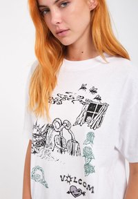 Witte katoenen t-shirt met abstracte zwarte en groene grafische prints, inclusief figuren en tekst, met een relaxed fit en ronde hals.