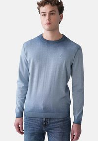 Helle blaue Strickjacke mit einem Verlaufdesign. Sie verfügt über einen gerippten Halsausschnitt und Bündchen. Kleines Logo auf der Brust. Lässige Passform.