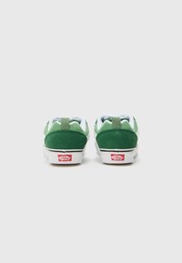Green suede sneakers with white soles, featuring a reinforced heel tab and prominent red Vans logo on the back.