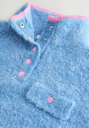 Blå tekstureret sweater med en lyserød ribkant, trykknapper og en blød, fuzzy finish. Har lyserøde knapdetaljer og en krave.