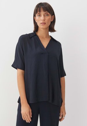 Marineblaue Kurzarmbluse mit einem eingeschnittenen Kragen, leichtem Stoff und legerem Schnitt. Nahtdetails verleihen eine subtile Struktur.