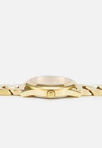 Gold watch with a round case, a textured bezel, and a prominent crown, featuring a linked metal bracelet in a matching gold finish.