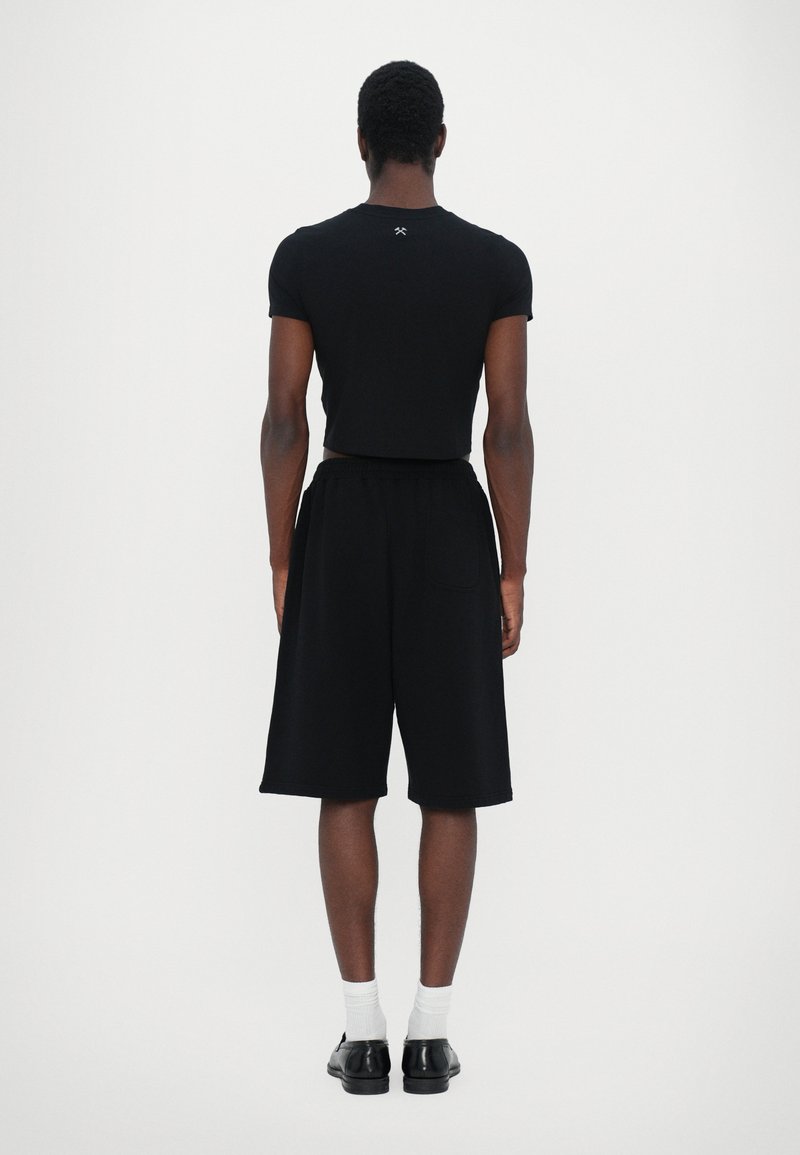 Black fitted short-sleeve shirt paired with loose black shorts, featuring an elastic waistband and side pockets. Solid colors with no patterns.