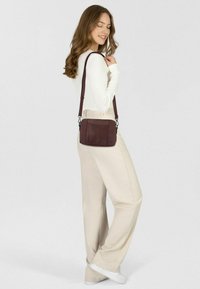 Dunkelburgunderfarbene Leder-Crossbody-Tasche mit strukturiertem Oberflächen, verstellbarem Tragegurt und silberfarbenen Beschlägen. Einfaches rechteckiges Design.