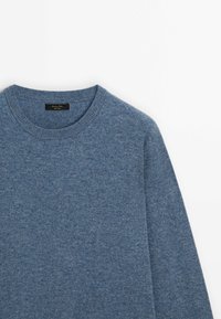 Niebieski sweter dzianinowy z okrągłym dekoltem, długimi rękawami i miękką teksturą. Etykieta widoczna przy dekolcie. Lekka i casualowa konstrukcja.